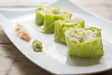 Salad roll vegetables with salad dressing in dish on wooden for