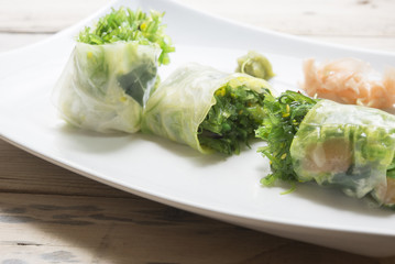 Salad roll vegetables with salad dressing in dish on wooden for