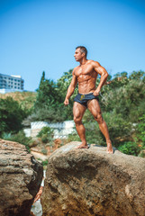 Man Athlete stands on a rock by the sea against the sky