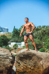 Man Athlete stands on a rock by the sea against the sky