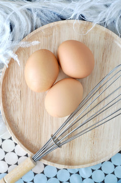 eggs on wooden plate with feather on background