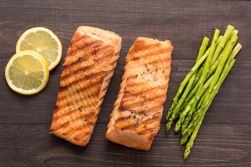 Grilled salmon with lemon, asparagus on the wooden background