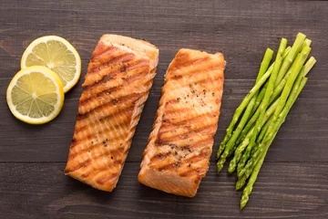 Grilled salmon with lemon, asparagus on the wooden background © Delicious