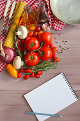 Obraz na płótnie Canvas Spices, pasta and vegetables around notebook.