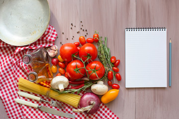 Notepads recipes on a wooden table. Fresh vegetables.
