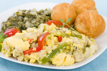 Fototapeta na wymiar Ackee & Saltfish - Traditional Jamaican dish made of salt cod and ackee fruit. Served with callaloo and johnny cakes. 