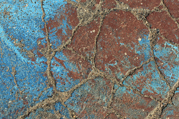 Blue and brown paint on damaged asphalt.