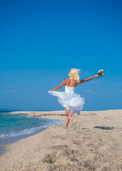 Young bride in wedding drees having fun on the beach