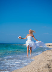 Fototapeta na wymiar Young bride in wedding drees having fun on the beach