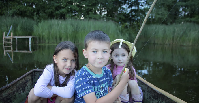 Portrait of three children fishing in a boat