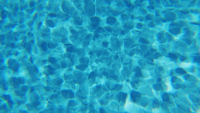Underwater sunlight reflections in swimming pool. Caustics ripple in blue water