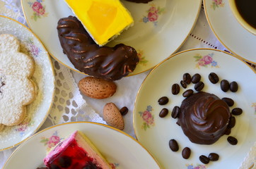 Desserts with cup of coffee, coffee beans and almonds on white tablecloth
