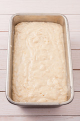 raw bread dough in a baking dish on wooden table