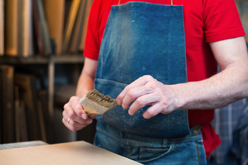 An artist priming canvas with paintbrush