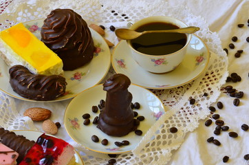 Desserts with cup of coffee, coffee beans and almonds on white tablecloth