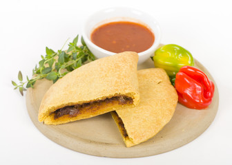 Fototapeta na wymiar Caribbean Jerk Beef Patty - Jamaican spicy minced jerk beef with onions and peppers in short crust pastry served with spicy sauce and scotch bonnet chillies. 