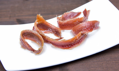 Anchovy fillets on tray on wooden table