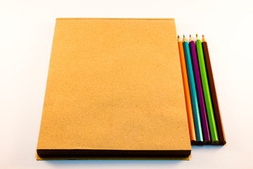 brown paper notebook with pencils