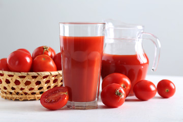 Fresh red tomatoes in basket and tomato juice in glass and jug o