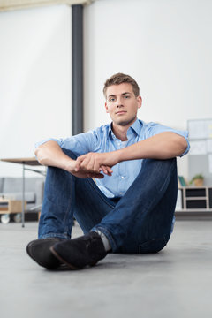 junger mann sitzt auf dem fußboden in einem modernen apartment