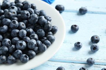 Blueberries in plate on a blue wooden background