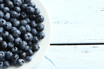 Blueberries in plate on a blue wooden background