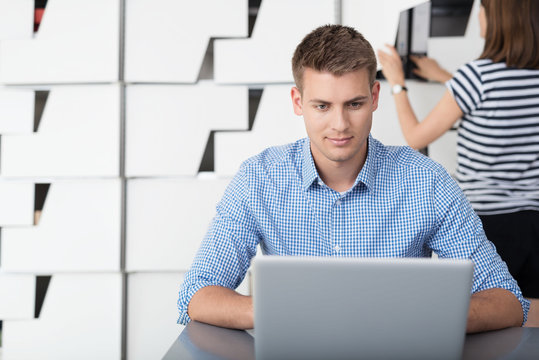 mann im büro schaut konzentriert auf laptop