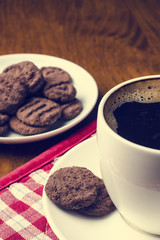 Cup of coffee with biscuit on a wooden table