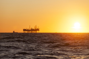 Obraz na płótnie Canvas Silhouette of oil platform at sunset