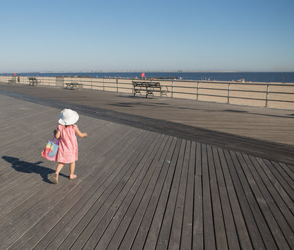 Little girl walking on the boardwalk in a sunny day. Photographed in Coney Island, Brooklyn, NY, USA in September 2015.