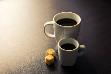 Cup of espresso  and mug of long coffee with sugar, warm colors