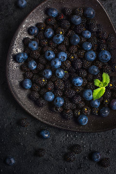 Fresh blackberry and blueberry on black plate.