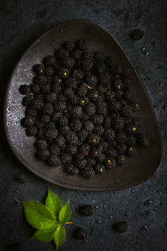 Fresh blackberry on black plate.