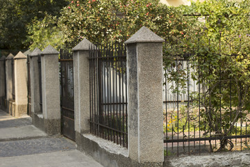 Forged fence between concrete columns