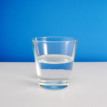 Half Empty Or Half Full Glass Of Water On White Table On Blue Background. (#2)