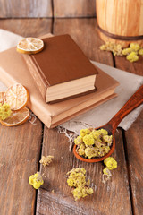 Old books with dry flowers and lemon on table close up