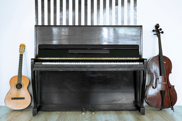 Cello and guitar near piano on white wall background © Africa Studio