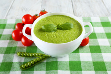 Tasty peas soup and cherry tomatoes on table close up