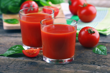 Glasses of tomato juice on wooden table, closeup