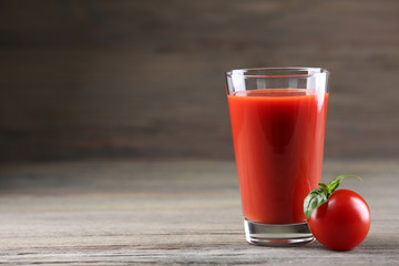 Glass of tomato juice with vegetable on wooden background