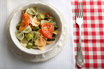 Roasted asparagus and tasty pasta with vegetables in bowl on wooden table background