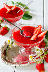 Strawberry jelly with fresh fruit on a white wooden background
