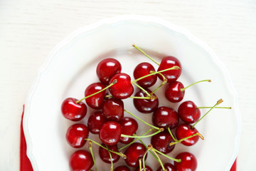 Obraz na płótnie Canvas Sweet cherries on plate, on light background