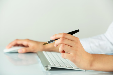 Female hands holding pen and computer mouse on light background