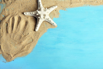 Fototapeta na wymiar Print of human hand on sand with starfish on wooden background