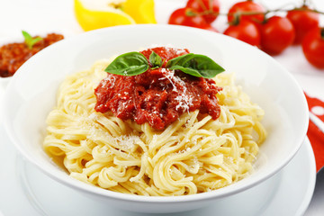 Spaghetti with tomato sauce and cheese on white plate, on color wooden background