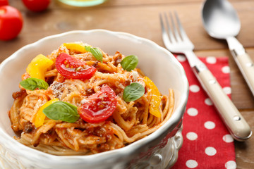 Homemade Spaghetti Bolognese with parmesan cheese in white bowl, on color wooden background