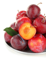 Ripe plums in metal plate isolated on white