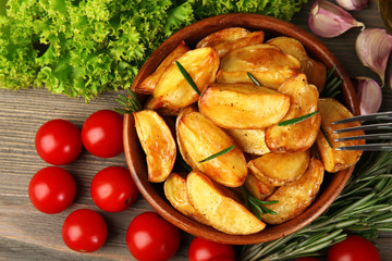 Baked potato wedges on wooden table, top view
