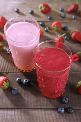 Glasses of berry smoothie on wooden table, closeup